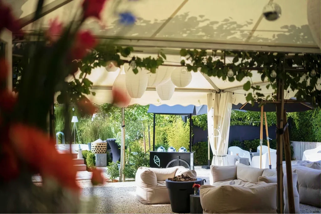 Lounge met witte banken onder een tent met bloemen