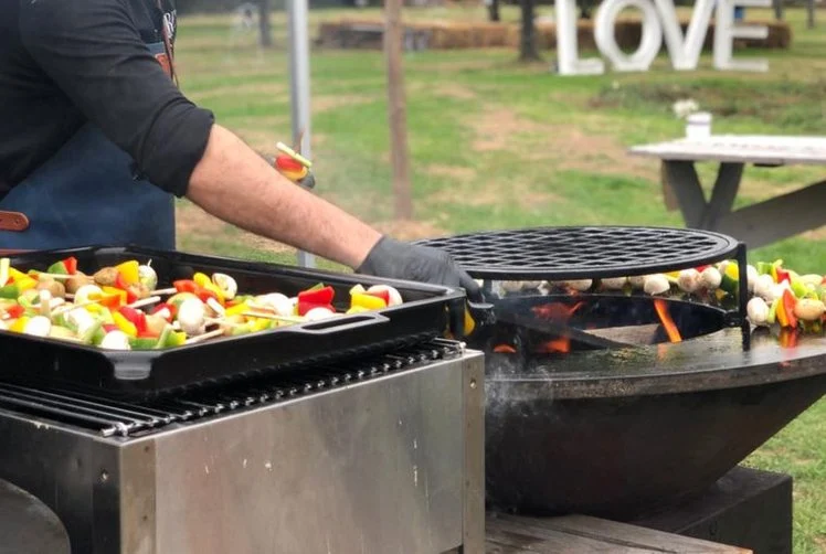 Kok grilt groenten en vlees op een vuurschaal-barbecue