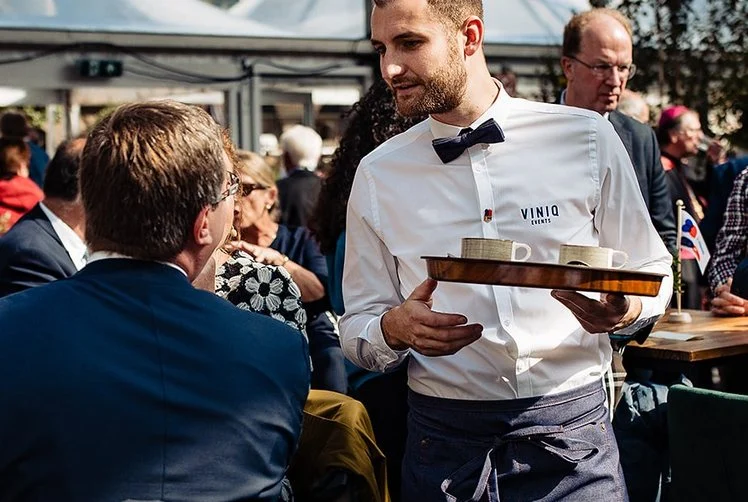 Ober in wit overhemd serveert gasten op een evenement