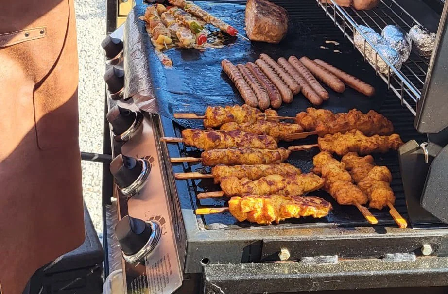 Kipspiesen en worstjes op een grote barbecue
