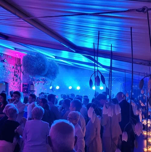 Feestende gasten in een tent met blauw en paars licht