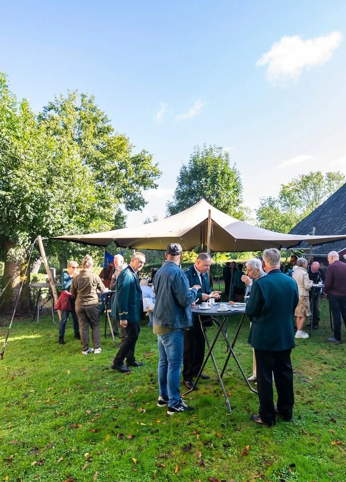 Collega's met een drankje op het gras bij een tent