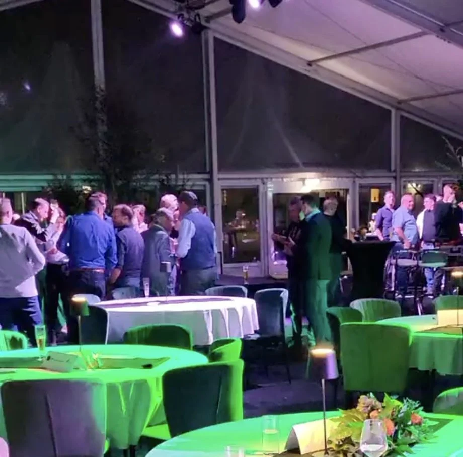 Gasten aan tafels met groene verlichting in een tent