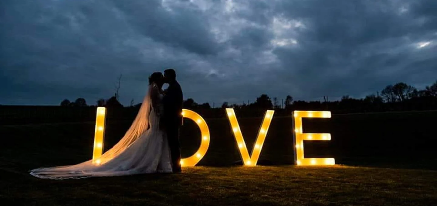 Bruidspaar in de avond naast verlichte LOVE-letters