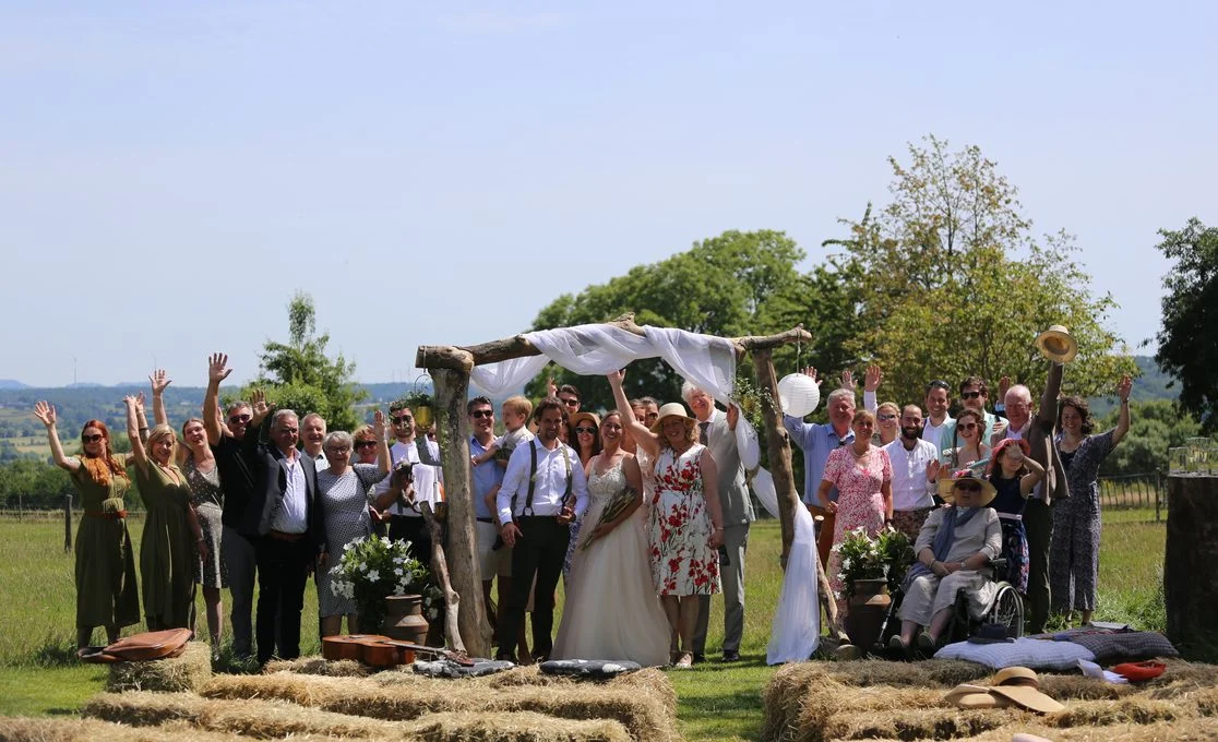 Bruiloftsgasten juichen bij een ceremonieboog in het veld