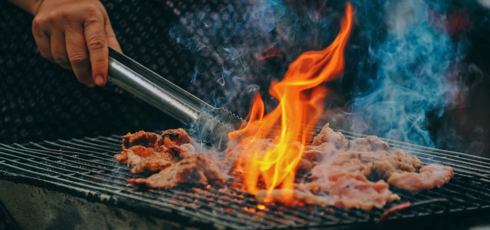 Vlees op de grill boven hoog oplaaiende vlammen
