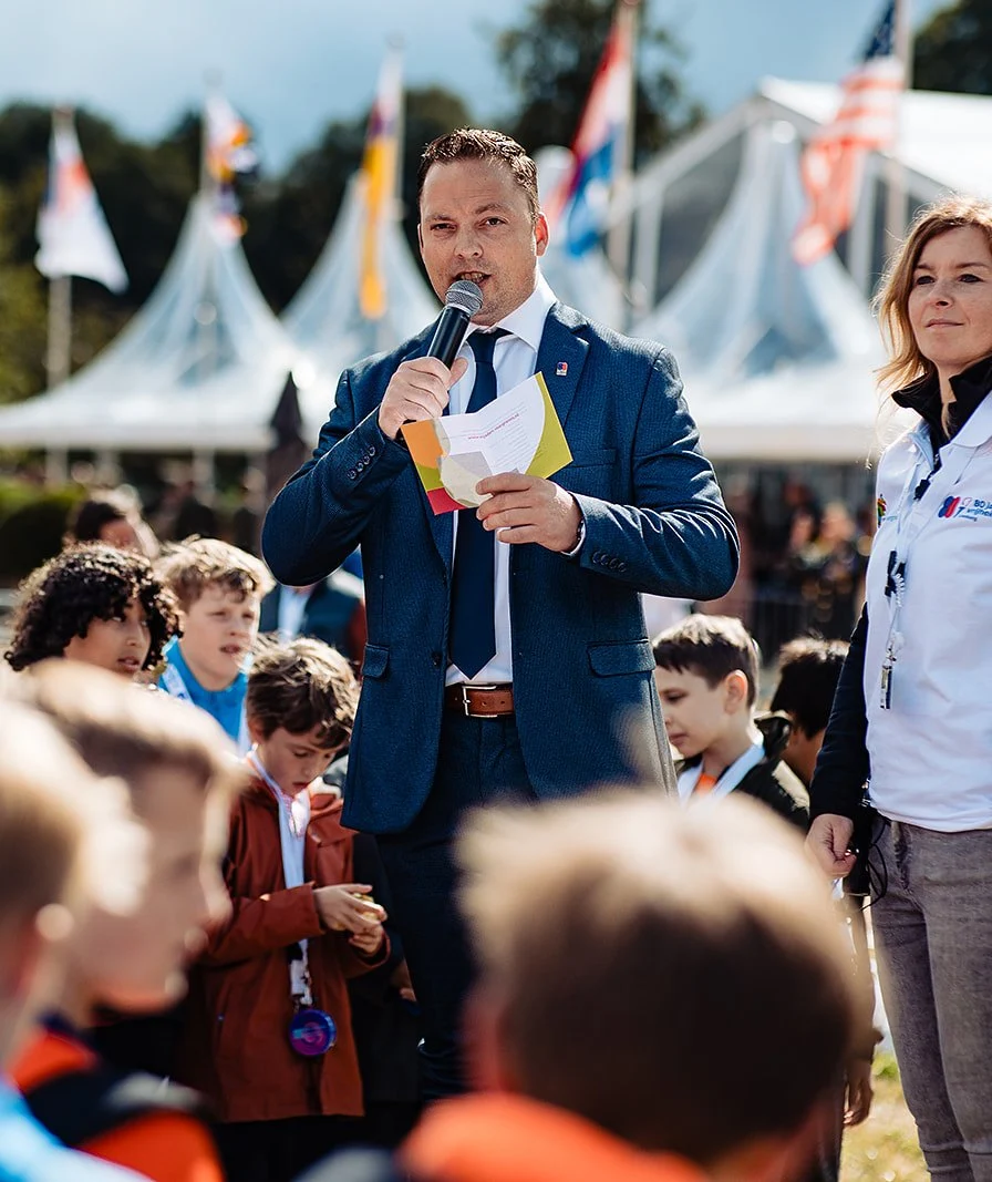 Spreker vertelt voor een publiek bij witte tenten