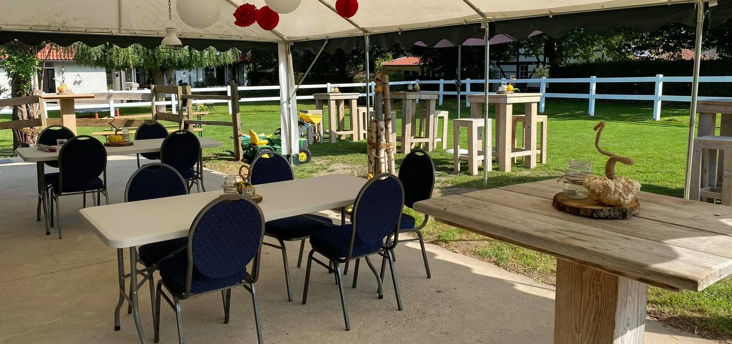 Tafels en stoelen onder een tent op een terrein