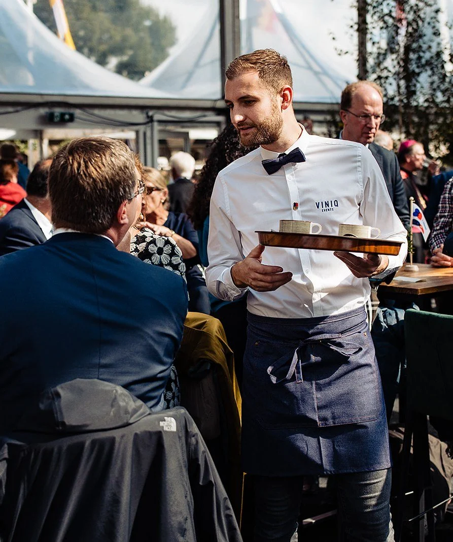 Ober met een dienblad tussen de gasten