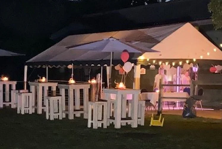 Verlichte partytent met witte statafels in de avond
