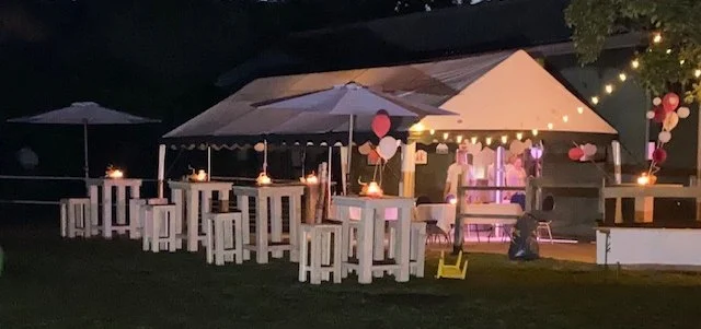 Partytent met statafels en ballonnen in de avond