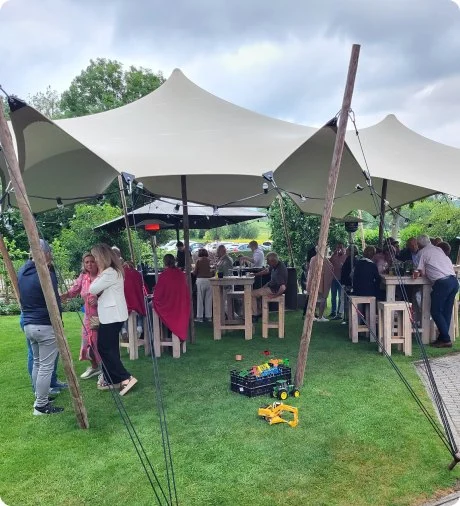 Gasten onder een stretchtent in het gras