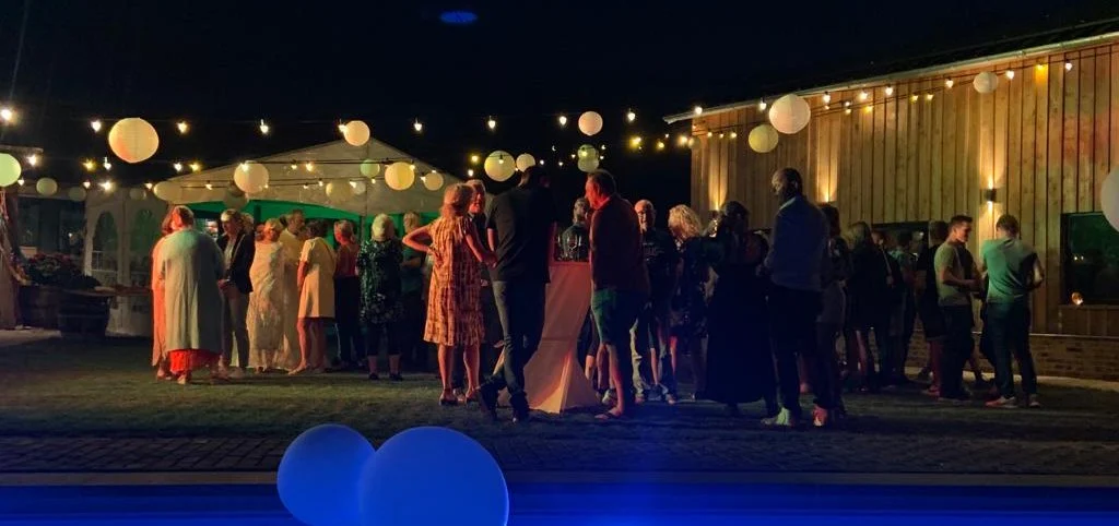 Gasten bij een verlichte tent in de avond