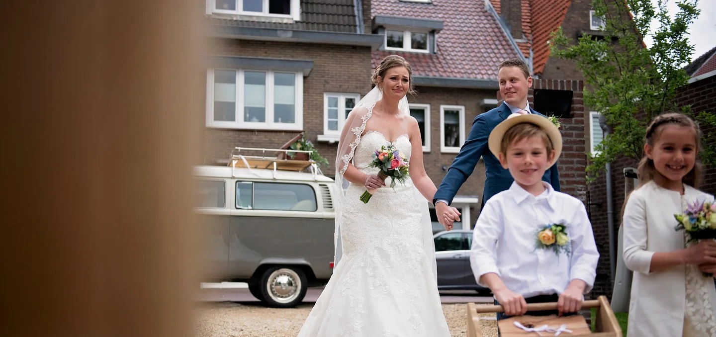 Bruidspaar met kinderen bij een oude bus