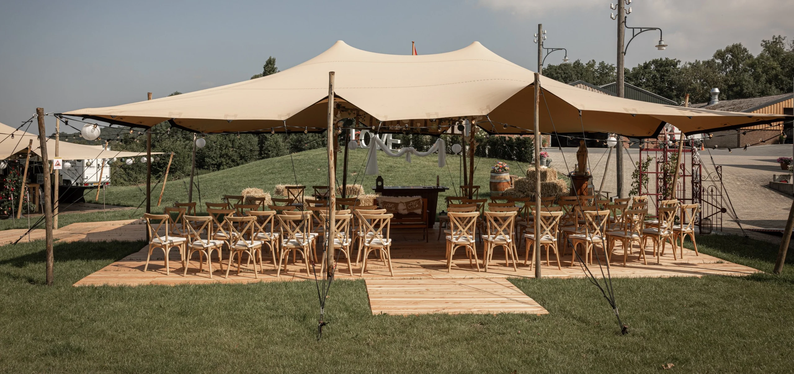 Stretchtent met houten stoelen in het gras