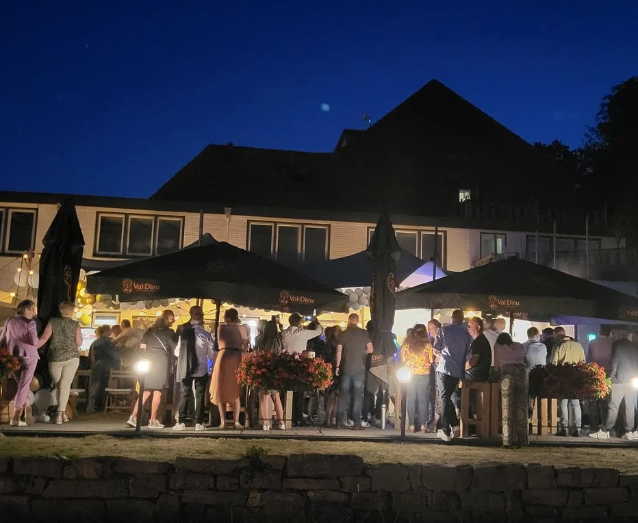 Gasten op een terras met parasols in de avond