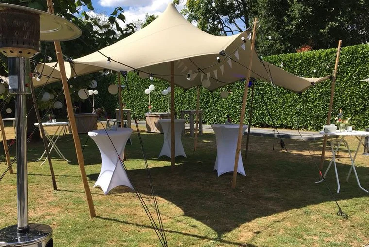 Stretchtent met statafels in een tuin