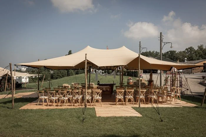Stretchtent met houten stoelen in het gras