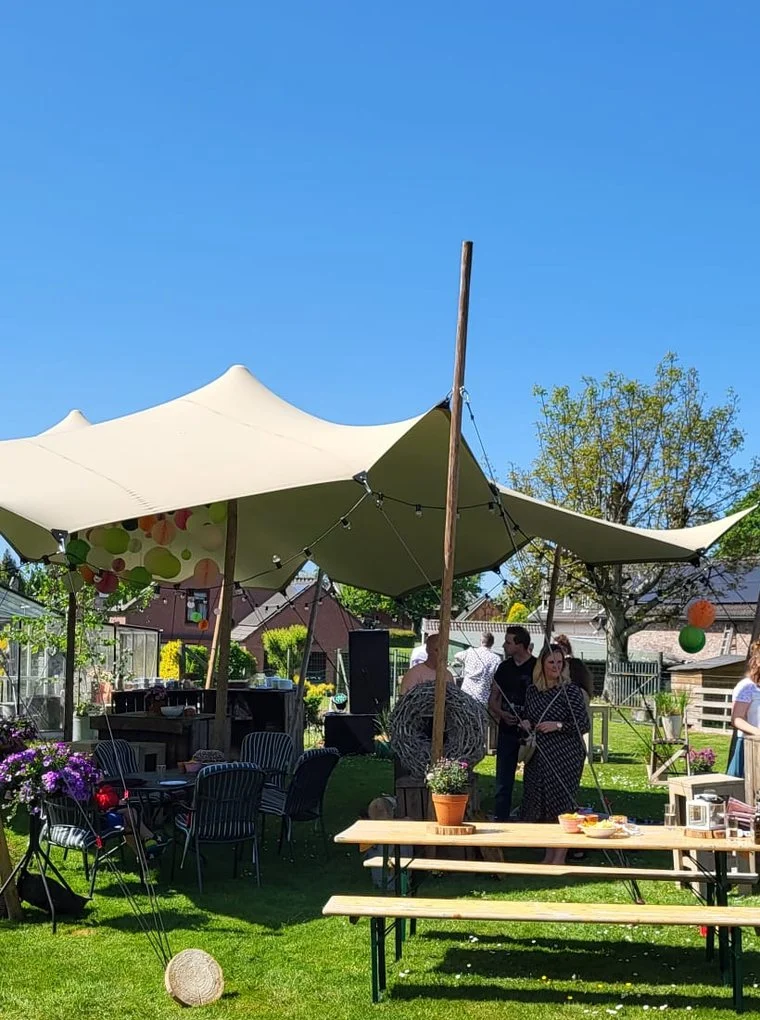 Stretchtent met picknicktafels in een tuin
