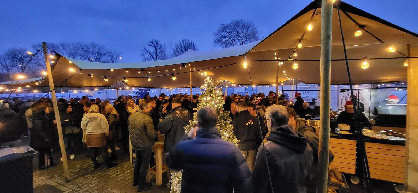 Gasten onder een stretchtent met lichtjes