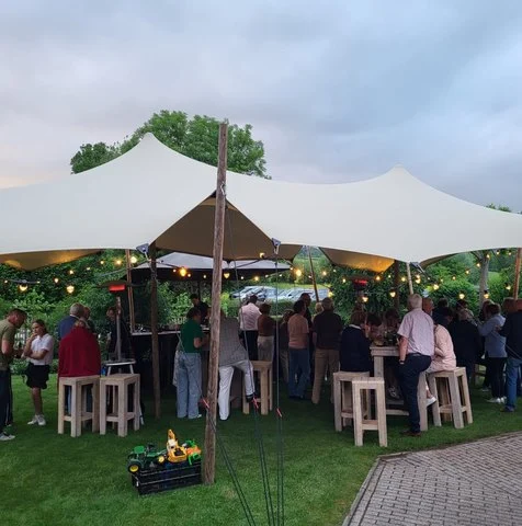 Gasten onder een stretchtent met lichtjes